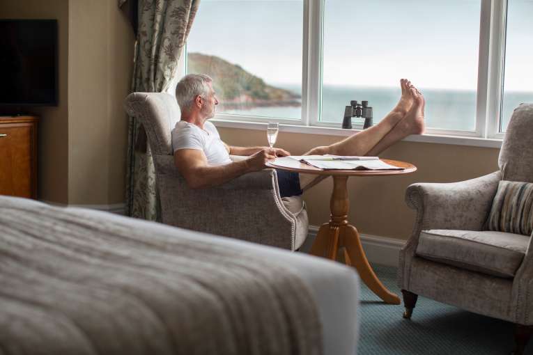 Male guest with his feet up enjoying a stunning sea view from his hotel room