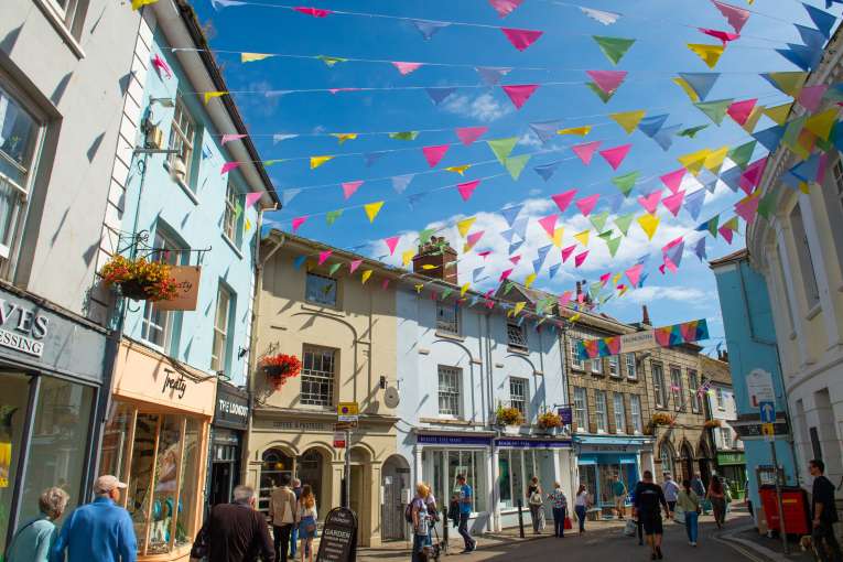 Colourful bunting flying between shops on summers day in Falmouth High Street