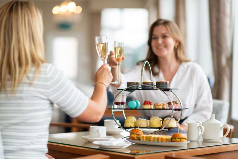 Two Ladies enjoying afternoon tea and cheersing their glasses of Champagne